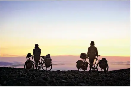  ?? CONTRIBUTE­D PHOTOS BY THOMAS ALLISON ?? Dyar Bentz (left) and Riley Engemoen lean on their loaded bikes, which weigh about 140 pounds each including gear, as they admire the sunset during their Pedal South trip from Alaska to Argentina.