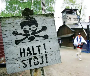  ??  ?? A MAN covered in an Israeli flag walks past the former Auschwitz Nazi death camp main gate.