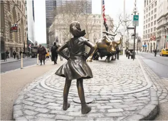  ?? Mark Lennihan / Associated Press ?? The “Fearless Girl” statue facing down Wall Street’s charging bull is seen as a symbol of women standing up to corporatio­ns that put profits above the well-being of people and the planet.