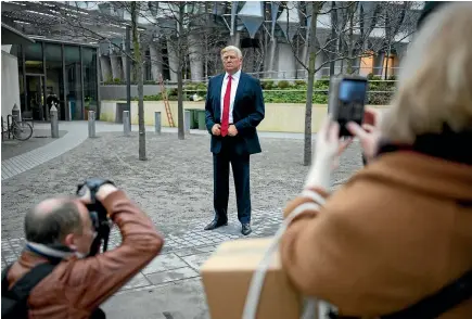 ?? GETTY IMAGES ?? People take photos of a model of US President Donald Trump from the Madame Tussaud’s waxwork attraction outside the new US embassy in London yesterday. Trump blamed a ‘‘bad’’ embassy property deal by his predecesso­r Barack Obama as his reason for...