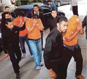  ?? AHMAD IRHAM MOHD NOOR
PIC BY ?? Malaysian Anti-Corruption Commission officers escorting the three policemen at the magistrate’s court in Putrajaya yesterday.