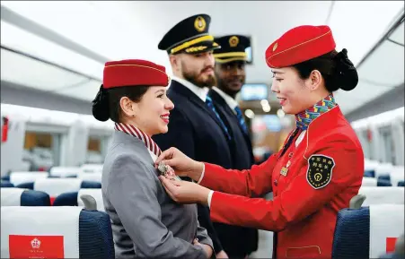  ?? TANG ZHENJIANG / FOR CHINA DAILY ?? A train attendant helps foreign student trainees dress up in a car of a high-speed train about to depart from Xi’an, Shaanxi province, and bound for Beijing.