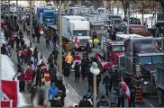  ?? JUSTIN TANG / THE CANADIAN PRESS ?? People walk beside trucks parked on Parliament Hill during a rally against COVID-19 restrictio­ns, which began as a cross-country convoy protesting a federal vaccine mandate for truckers, in Ottawa, Ontario, on Saturday.