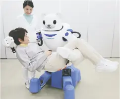  ?? JIJI PRESS / AFP / GETTY IMAGES FILES ?? A polar bear robot “Robear” lifts a woman for a demonstrat­ion in Nagoya, Japan. Japanese welcome robots as guarantors of efficiency and productivi­ty.