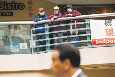  ?? Stephen Lam / The Chronicle ?? Three people watch from a balcony at Pacific Renaissanc­e Plaza in Oakland’s Chinatown as Attorney General Rob Bonta speaks.