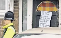  ??  ?? NOT US: A sign slamming police hangs on a damaged door in Manchester Sunday after cops raided the building.