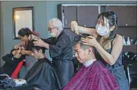  ?? Allen J. Schaben Los Angeles Times ?? KYLEE LIU, right, cuts Anthony Arevalo’s hair at Hair Event in Fullerton on May 26, the salon’s reopening day after the initial shutdown amid the pandemic.