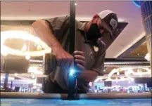  ?? Photos and text from The Associated Press ?? Dean Loveland, a worker at the Hard Rock casino in Atlantic City N.J., installs plexiglass barriers between player positions at a card table at the casino a week before it was to reopen amid the coronaviru­s outbreak.