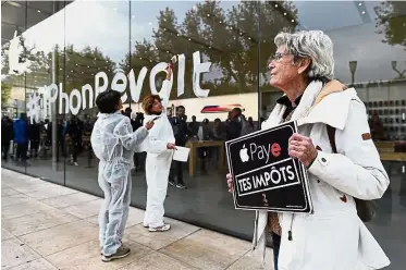  ??  ?? Making her point: A woman holding a sign reading ‘Apple pay your taxes’ during a protest against tax evasion on the release day of the new iPhone X in Aix-enProvence, southern France. — AFP