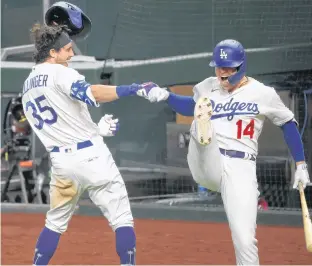  ?? USA TODAY SPORTS ?? Los Angeles Dodgers center fielder Cody Bellinger (35) celebrates with Los Angeles Dodgers second baseman Enrique Hernandez (14) after hitting a go-ahead home run in the seventh inning against the Atlanta Braves during Game 7 of the 2020 NLCS at Globe Life Field in Arlington, Texas on Sunday. Game 1 of the World Series goes tonight at 9 p.m.