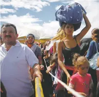  ?? ARIANA CUBILLOS/THE ASSOCIATED PRESS ?? People wait in lines to cross the border into Colombia through the Simon Bolivar Internatio­nal Bridge in San Antonio del Tachira, Venezuela.