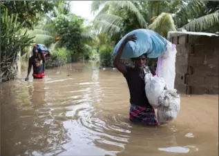  ?? DIEU NALIO CHERY, THE ASSOCIATED PRESS ?? In Haiti, Assilia Joseph, right, and her son Wisner Jean Baptiste carry belongings salvaged from their flooded home.