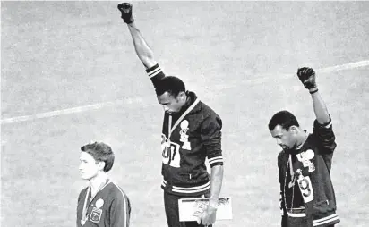  ?? AP ?? United States athletes Tommie Smith, center, and John Carlos, right, extend their gloved fists skyward during the playing of the national anthem after Smith received the gold medal and Carlos the bronze for the 200-meter run at the Mexico City Olympics on Oct. 16, 1968. Silver medalist Peter Norman, of Australia, is at left.