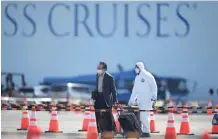  ?? CHARLY TRIBALLEAU / AFP VIA GETTY IMAGES ?? A passenger, left, leaves the Diamond Princess cruise ship in quarantine due to fears of the new COVID-19 coronaviru­s in Yokohama on Feb. 19.