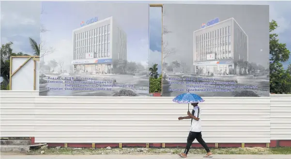  ?? PHOTO / AP ?? A man walks past a developmen­t site for a Chinese investment bank in Nuku’alofa, Tonga.