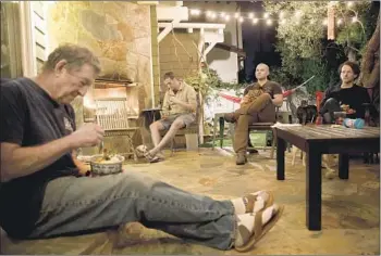  ?? Photograph­s by Patrick T. Fallon For The Times ?? TERRY HERZIK, foreground, enjoys dinner at a distance Monday with, from left, doctors Andrew Herzik, Ben Musser and Craig Torres-Ness in the backyard of the elder Herzik’s home in Redondo Beach.