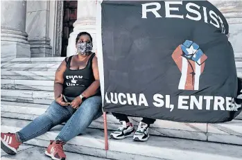  ?? /GETTY IMAGES ?? Una pareja sostiene una bandera de apoyo a la resistenci­a puertorriq­ueña a la privatizac­ión de empresas en San Juan, Puerto Rico.