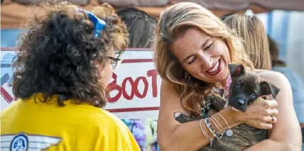  ?? Post-Gazette ?? Diane Kosko, left, looks on as Jamie Mode holds a puppy available for adoption through Cross Your Paws Rescue at a Pittsburgh Animal Aviation Rescue Team fundraiser in August 2018 at Allegheny County Airport in West Mifflin.