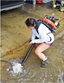  ?? STAFF PHOTO BY JOHN RAWLSTON ?? Leani Drapiza uses a leaf blower to unclog a drain so water can
escape the flooded garage
of her Brainerd
home Thursday afternoon.