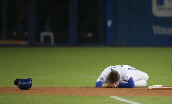  ?? STEVE RUSSELL/TORONTO STAR ?? Blue Jays third baseman holds his head on the field after a collision with Texas Rangers second baseman Rougned Odor in the fourth inning Thursday. Donaldson left the game the next inning.