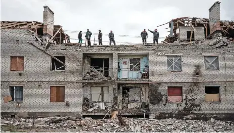  ?? (AFP) ?? Workers clean rubbles atop a buidling destroyed by shelling a month ago in Cherkaske, eastern Ukraine on Wednesday