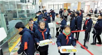  ??  ?? Students at the Minhang school get ready to enjoy their lunch.