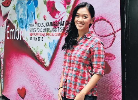  ?? KOSOL NAKACHOL ?? Ms Adisara stands in front of a billboard showing one of Tangmo’s newly designed items.