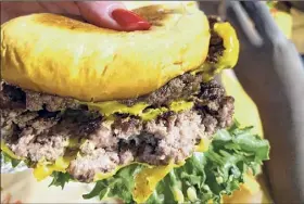  ?? Susie Davidson Powell / For the Times Union ?? Biting into a burger at Prime Burger and Shakehouse at the River Street Market food hall in Troy .