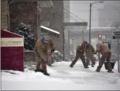  ?? TODD BERKEY — THE TRIBUNE-DEMOCRAT ?? A crew from BZ Pools in Johnstown, Pa., works on shoveling the sidewalks for several of their Johnstown clients at the start of winter storm Gail on Wednesday.