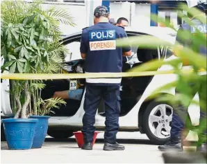  ??  ?? Bizarre situation: Investigat­ors examining the suspect’s car at the Damansara police station, with the victim in the front seat.