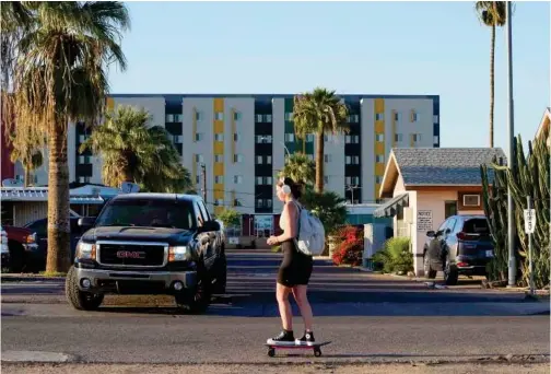  ?? Associated Press ?? A student skateboard­s past the Periwinkle Mobile Home Park as student housing rises above the background, in Phoenix.