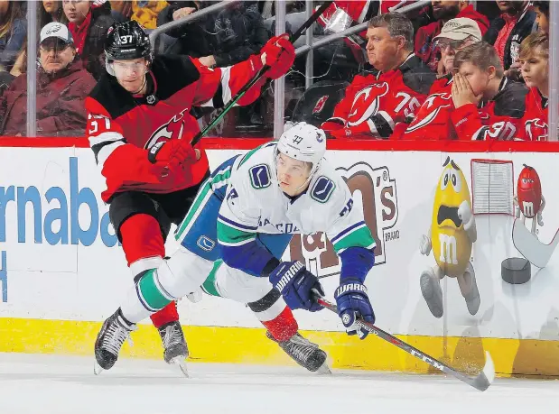  ?? — GETTY IMAGES ?? Young Canucks winger Nikolay Goldobin, pictured flying through the air after taking a cross-check from Devils centre Pavel Zacha during a recent game, finds himself in head coach Travis Green’s doghouse over his lack of attention to the defensive details of the game.