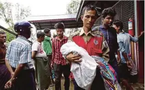  ?? [ FOTO EPA ] ?? Sukarelawa­n Palang Merah mendukung kanak-kanak yang hilang tempat tinggal di Maungdaw.