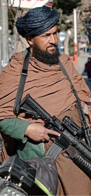  ?? ?? Life in the shadow of the Taliban: A woman walks past an armed guard in Kabul, Afghanista­n, last month. The woman pictured did not participat­e in this article