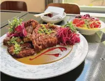  ?? ?? A crispy fried pork chop is topped with apple curry gravy and pickled cabbage. Appetizers include a housemade pickle plate.