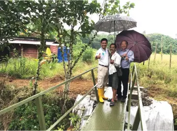  ??  ?? Lai (centre) is all smiles atop the new steel bridge leading to his house.