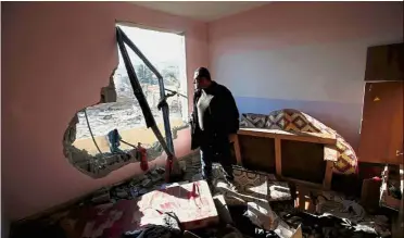  ?? — Reuters ?? Collateral damage: A Palestinia­n looking at a targeted building from his apartment that was damaged in an Israeli air strike in the northern Gaza Strip.