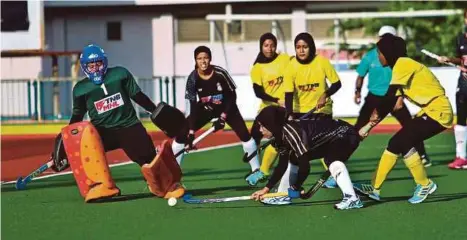  ?? [FOTO GHAZALI KORI /BH] ?? Pemain TLHT, Nur Faizah Md Sauti (dua dari kanan) dihalang penjaga gol PSHA-MSSPP, Nur Aisyah Hamidi dalam perlawanan di Stadium Hoki Batu Buruk, Kuala Terengganu, semalam.