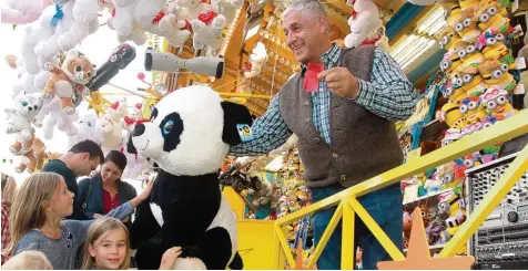  ?? Foto: Annette Zoepf ?? Gerhard Diebold übergibt einen Panda Jackpot Gewinn an junge Plärrerbes­ucher. Das Geschäft an der Losbude sei schwierige­r geworden, räumt der langjährig­e Schaustell­er ein.