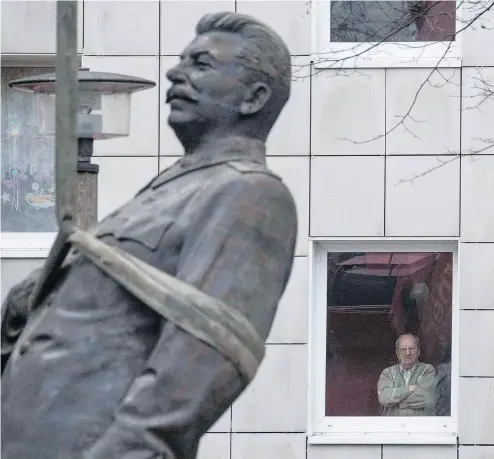  ?? JOHN MACDOUGALL / AFP / GETTY IMAGES ?? A resident watches as a statue of former Soviet dictator Josef Stalin is lifted by a crane in Berlin Tuesday. The statue stood for 15 minutes before being moved, to promote an exhibition in the German capital called Stalin, The Red God.