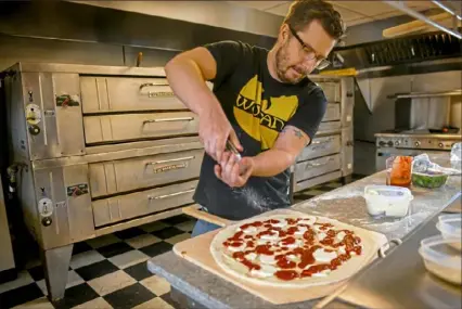  ?? Steve Mellon/Post-Gazette ?? Josh Sickels puts toppings on a pizza at Rockaway Pizzeria, his White Oak shop, on Friday.