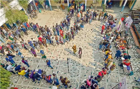  ?? — PTI ?? People wait in queues to cast their votes at Shaheen Public School polling station in the Shaheen Bagh area, which has been witnessing a peaceful protest against the Citizenshi­p Act for several weeks, during the Delhi Assembly elections in New Delhi on Saturday.