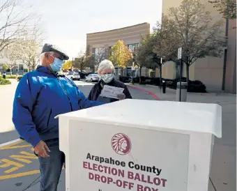  ?? Rachel Ellis, The Denver Post ?? Rusty Simmons and Rosalinda Calamari put their mail- in ballots in a dropbox outside of the Englewood Civic Center on Thursday.