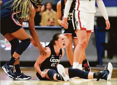  ?? Tyler Sizemore / Hearst Connecticu­t Media ?? UConn's Nika Muhl, center, celebrates with teammate Aaliyah Edwards, left, after drawing a foul in the Huskies' win over No. 10 NC State on Sunday.