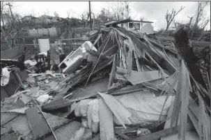  ?? The Associated Press ?? AFTERMATH: Jose Garcia Vicente walks through rubble of his destroyed home Monday in the aftermath of Hurricane Maria in Aibonito, Puerto Rico. The U.S. ramped up its response Tuesday to the humanitari­an crisis in Puerto Rico while the Trump...