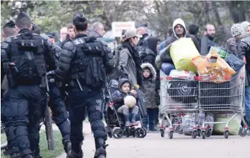  ?? — AFP ?? Migrants carry their belongings on Tuesday during a police operation to evacuate a migrant camp in Grande Synthe.