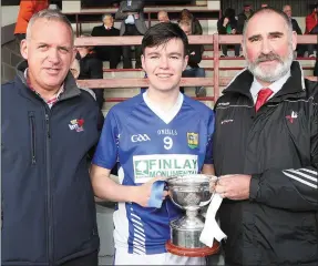  ??  ?? Liam Jackson of Ardee St. Marys accepts the trophy from Colm Corrigan of sponsors LMFM and Alan McGowan, Chairman of the MinorBoard.
