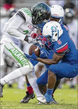  ?? ALLEN EYESTONE / THE PALM BEACH POST ?? Atlantic’s Matt Taylor and Pahokee’s Leroy Love wrestle for control of a punt in Friday’s matchup. Love was able to retain possession.