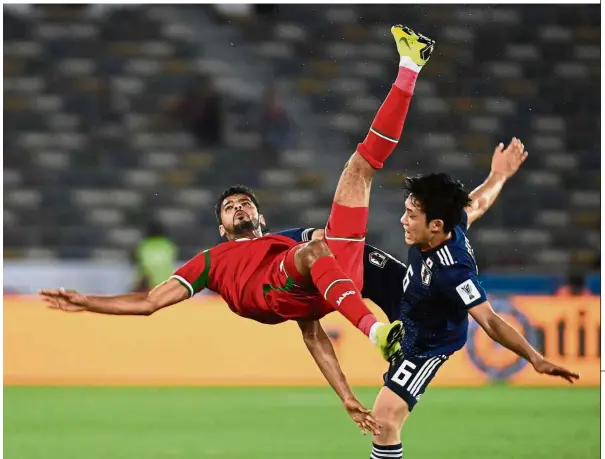  ?? — AFP ?? Airborne: Oman forward Muhsen Al Ghassani (left) fighting for the ball with Japan’s Wataru Endo during the Asian Cup Group F match in Abu Dhabi on Sunday.