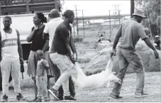  ??  ?? Two men carry a goat for slaughter at Kelvin industrial area, Bulawayo, ahead of Christmas Day celebratio­ns today. — Picture by Cordelia Mondela